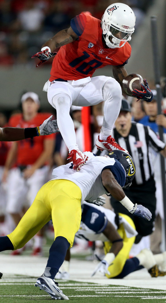 Arizona wide receiver Samajie Grant (10) uses Northern Arizona safety LeAndre Vaughn (4) as step while hurdling over defenders to pick up extra yards after a sideline catch in the second quarter of their game at Arizona Stadium, Saturday Sept. 19, 2015, Tucson, Ariz.  Kelly Presnell / Arizona Daily Star