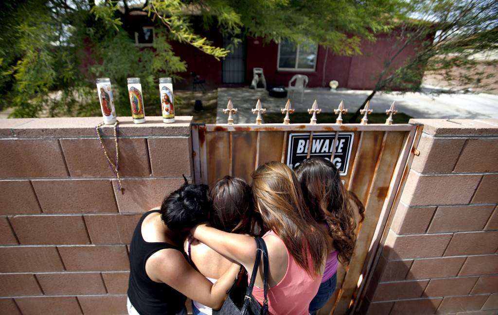 Friends of 17-year-old Isela Rodriguez hold each other outside the home in the 800 block of west Calle Medina where Rodriguez and four others were found dead Tuesday, after leaving a memorial candle, Wednesday, May 13, 2015, Tucson, Ariz. Kelly Presnell / Arizona Daily Star