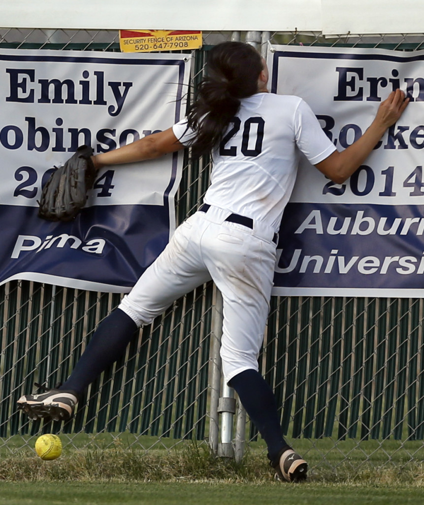 Ironwood Ridge's Merrilee Miller (20) slams head first into the centerfield fence chasing a fly ball by Canyon del Oro's Ellessa Bonstrom (10) that ended up a triple in the third inning of their game at Ironwood Ridge High School, Tuesday, April 14, 2015, Tucson, Ariz. Kelly Presnell / Arizona Daily Star